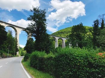 Road by arch bridge against sky