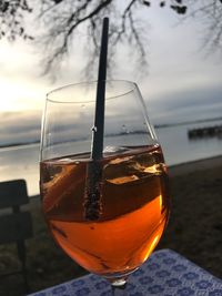 Close-up of wineglass on table against sky during sunset