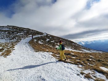 Woman on snowcapped mountain against sky