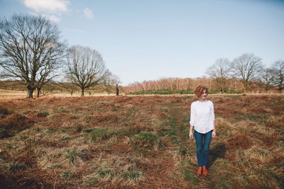 Full length of woman standing on field against sky