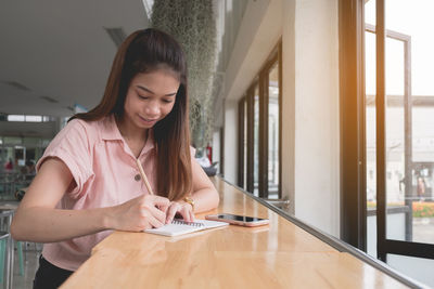 Young woman using smart phone on table