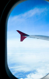 Close-up of airplane wing against clouds