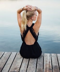 Young woman sitting on pier by lake