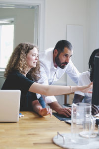 Businesswoman discussing with colleagues over computer in creative office