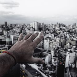 Close-up of hand against buildings in city