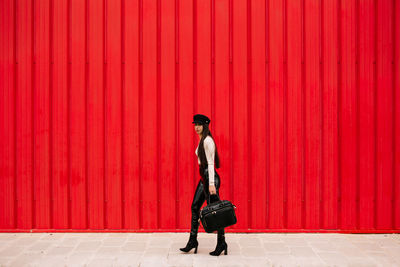 Full length of man walking against red wall