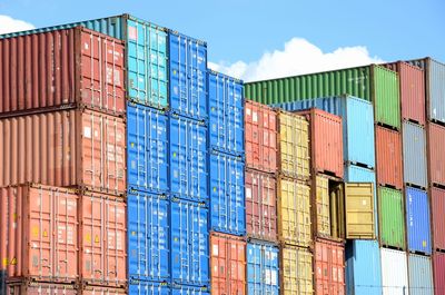 Stack of multi colored containers at harbor against sky