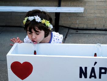 Girl drinking water at drinking fountain in park