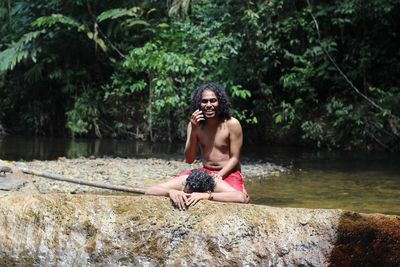 Happy men on rock in forest