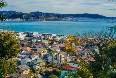 High angle view of townscape by sea against sky