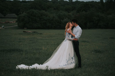 Couple kissing while standing on grass