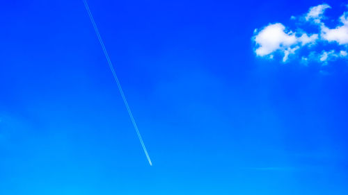 Low angle view of vapor trails in blue sky