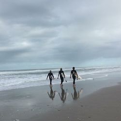 People playing on beach against sky