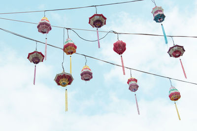 Low angle view of lanterns hanging against cloudy sky