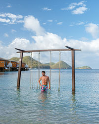 Rear view of woman standing in sea against sky