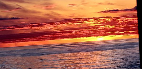 Scenic view of sea against dramatic sky during sunset