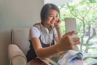 Young woman using mobile phone while sitting on sofa at home