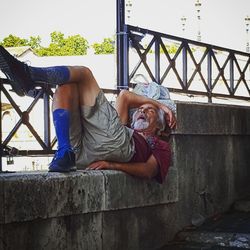 Portrait of man sitting on bridge against wall