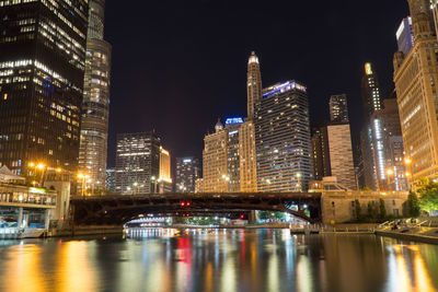 Illuminated buildings by river at night