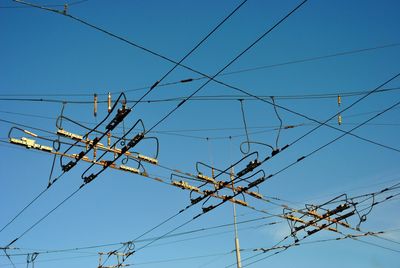 Low angle view of electricity pylon against blue sky