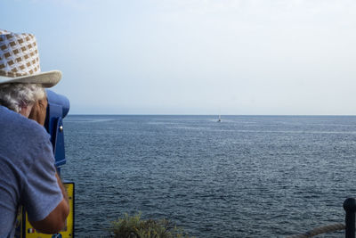 Rear view of man looking through coin operated binoculars