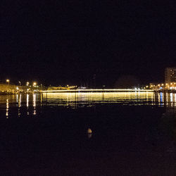 Reflection of illuminated sky on calm sea at night