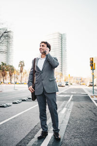 Businessman talking on phone while standing on road