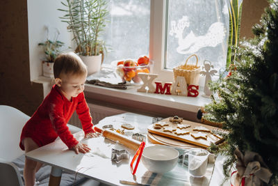 Cute little baby toddler girl making christmas cookies in home kitchen and play with dough. mother
