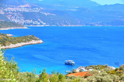 High angle view of sea and mountains against blue sky