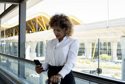 Stewardess with her suitcase using her smartphone