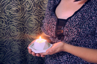 Midsection of woman holding sparkler at home