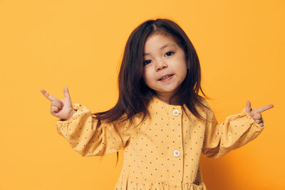 Portrait of young woman standing against yellow background