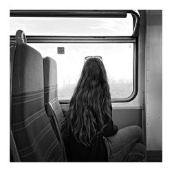 Rear view of woman looking through train window