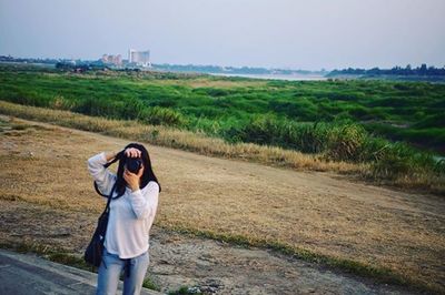 Woman photographing on landscape against sky