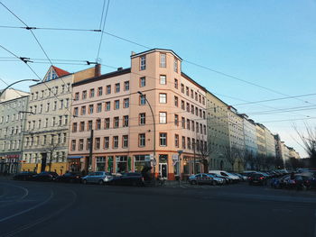 Cars on road by buildings against sky in city