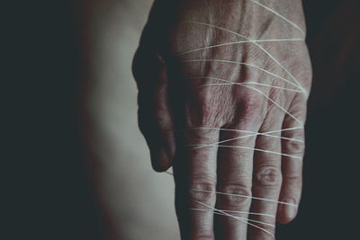 Cropped image of hand tied with thread in darkroom