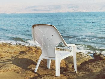 Deck chairs on beach against sky