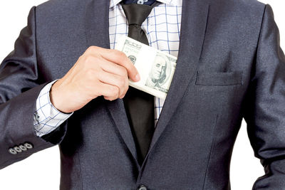 Midsection of businessman with paper currency against white background