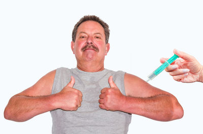 Optical illusion of man showing thumbs up sign while being injected against wall