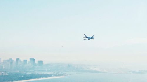 Airplane flying over sea against clear sky