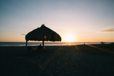 Silhouette people on beach against sky during sunset