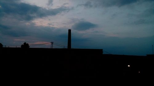 Low angle view of silhouette built structure against cloudy sky