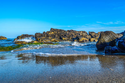 Surface level of rocks on shore against blue sky