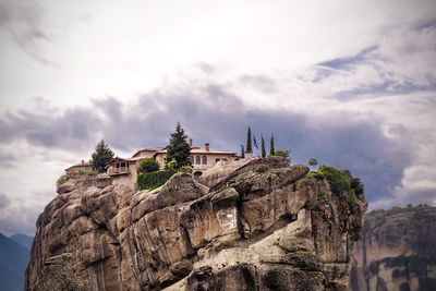 Low angle view of meteora on rock formation at kalabaka against sky