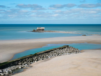 Ancient fort surrounded by water on a sandy beach with a mole in the foreground