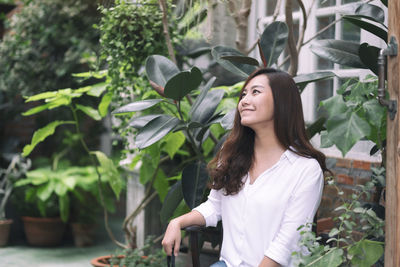 Woman sitting against plants