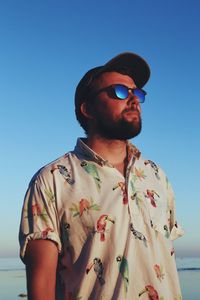 Man wearing sunglasses while standing at beach during sunset