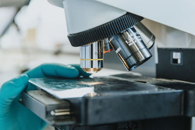 Close-up of woman hand placing human brain microscope slide under microscope at laboratory