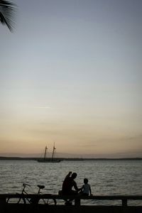 Silhouette people on beach against clear sky