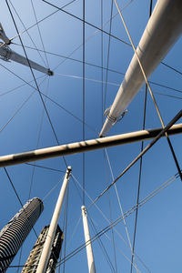 Low angle view of bridge support structures against clear blue sky